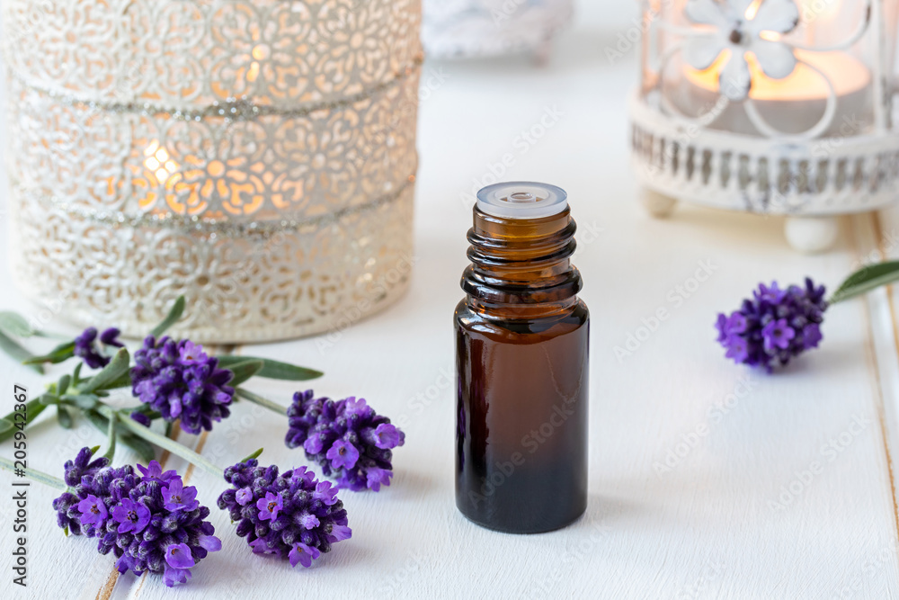 A bottle of essential oil with fresh blooming lavender A bottle of essential oil with fresh blooming lavender