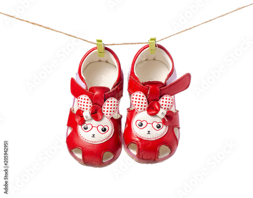 Baby shoes sandals clothespins rope on white background isolation