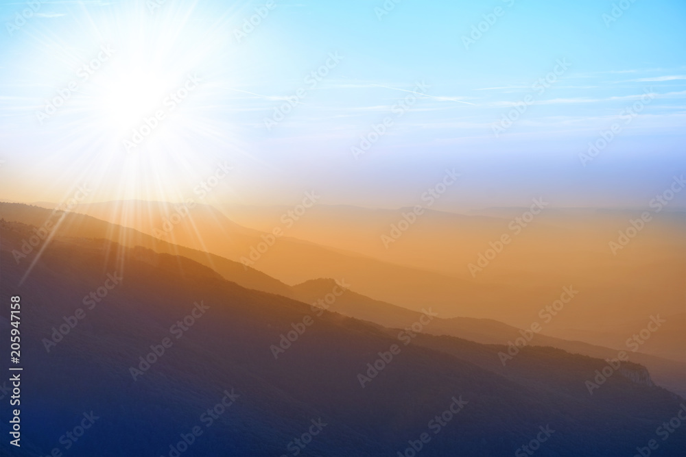 Beautiful sunset at the mountains. Colorful landscape with sun rays and blue sky