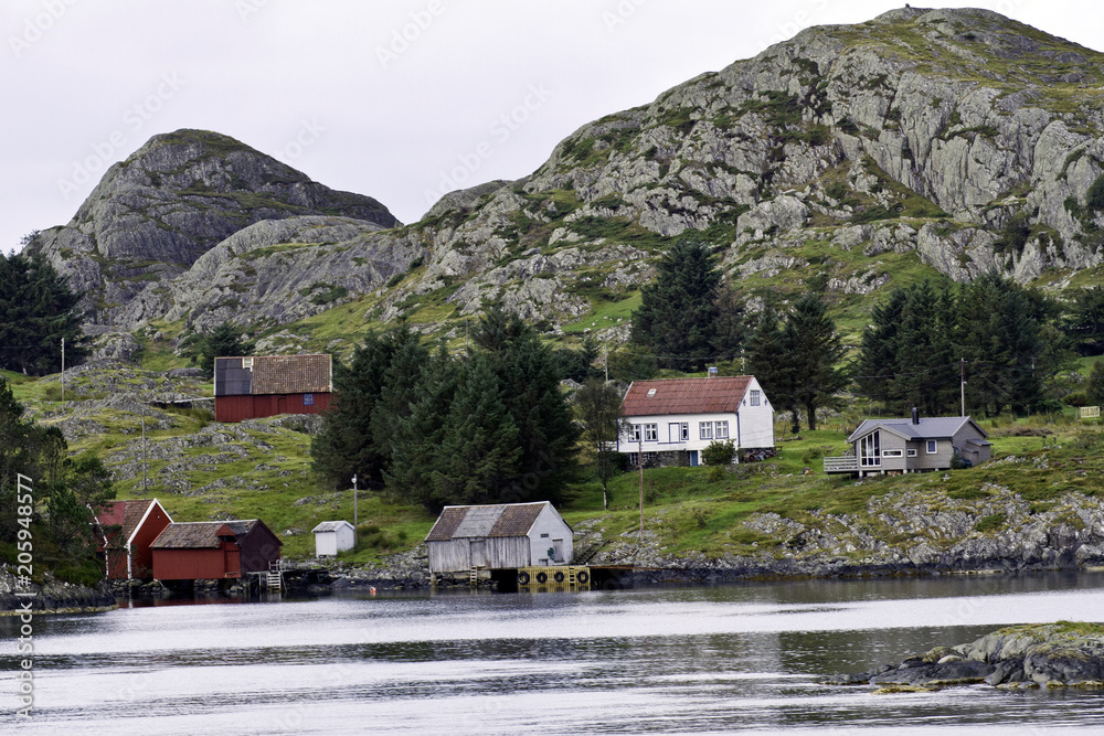 Homes under rocky mountains of the rugged  coastline near Bergen, Norway