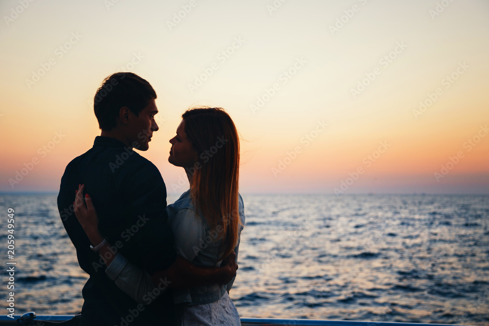 Silhouette of a couple at the beach at sunrise sky summer time, seashore summer beach at yellow blue evening horizon sea, sunset background