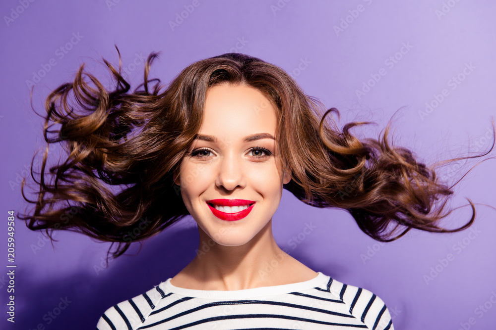 Portrait of pretty sexy girl with flying hair red lipstick white teeth enjoying wind blow looking at camera isolated on violet background. Haircare concept