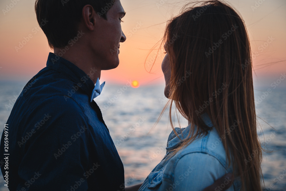 Close up of couple watching the sunrise at the beach summer time, seashore summer beach at yellow blue evening horizon sea, sunset background Close up of couple watching the sunrise at the beach summer time, seashore summer beach at yellow blue evening horizon sea, sunset background
