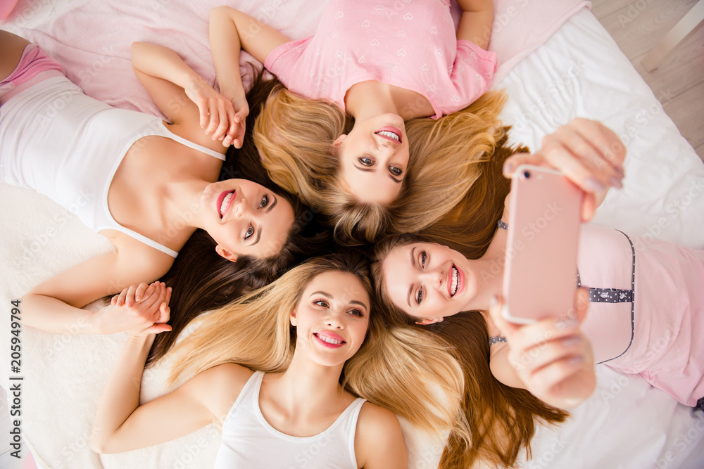Portrait of sexy, pretty, sweet, charming, funny, foolish, lovely, cheerful  girls lying head to head on bed using smart phone shooting selfie on front  camera, holding hands Stock Photo | Adobe Stock