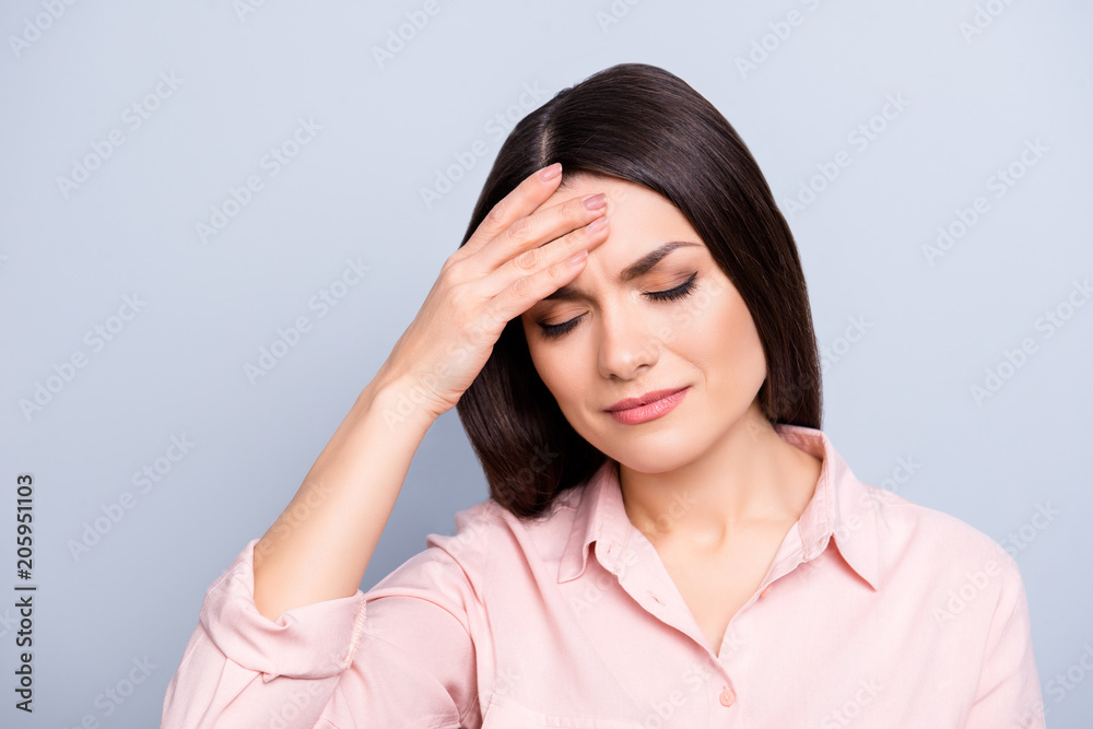 Portrait of upset, sad, tired, overworked, disappointed woman holding hand on forehead with close eyes suffering from spasm, syndrome, isolated on grey background, feeling bad Portrait of upset, sad, tired, overworked, disappointed woman holding hand on forehead with close eyes suffering from spasm, syndrome, isolated on grey background, feeling bad