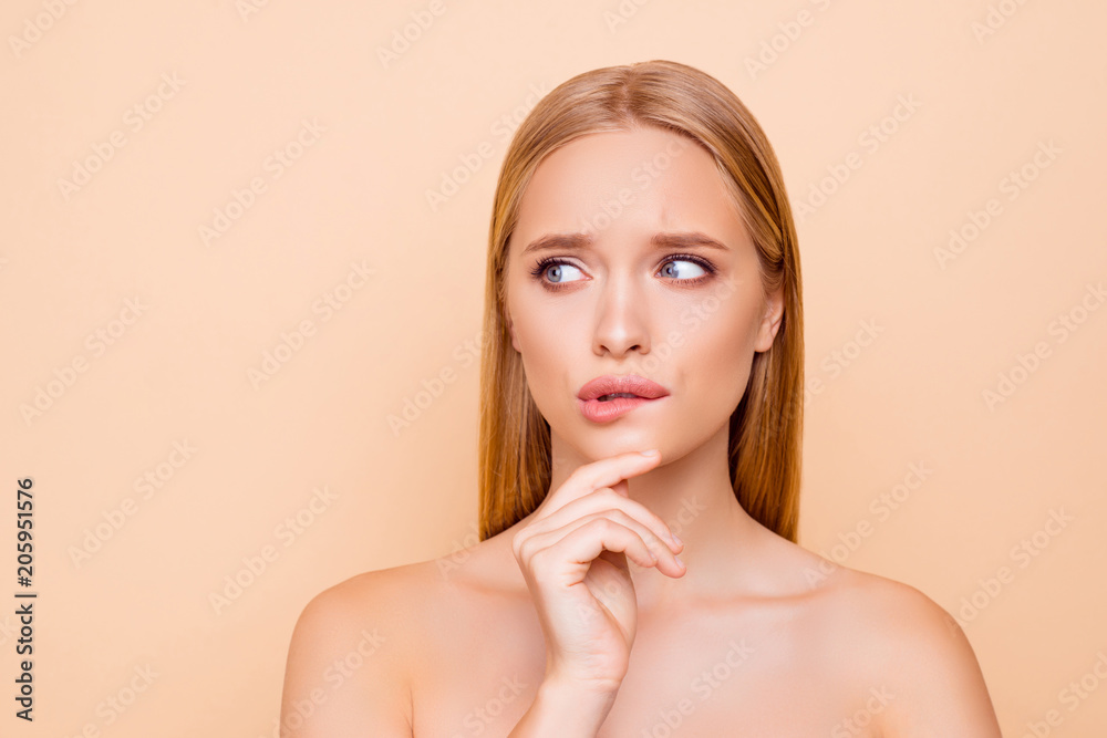Serious, concentrated, thoughtful, attractive woman holding hand on chin looking to the side with eyes trying biting low lip with teeth, isolated on beige background wellness wellbeing concept - obrazy, fototapety, plakaty 