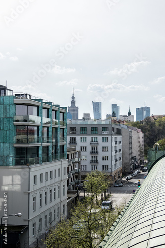 urban landscape with people cars and apartments and other buildings seen from the roof of a modern building on an early spring day