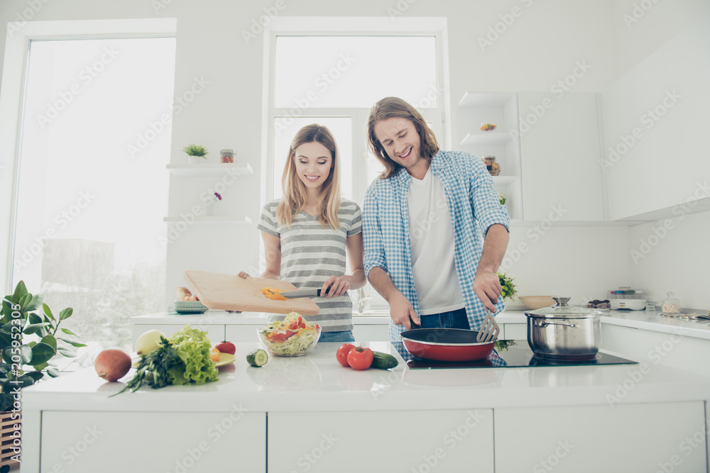 Front view portrait of cheerful positive couple preparing dinner together keeping healthy lifestyle enjoying weekend vacation holiday together. Weightloss fitness concept Front view portrait of cheerful positive couple preparing dinner together keeping healthy lifestyle enjoying weekend vacation holiday together. Weightloss fitness concept
