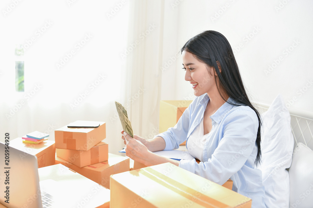 Sme business concept. Young people are packing their packages.Delivery business Small and Medium Enterprise (SMEs). Young Owner Start up for Business Online. Beautiful girls are counting money. Sme business concept. Young people are packing their packages.Delivery business Small and Medium Enterprise (SMEs). Young Owner Start up for Business Online. Beautiful girls are counting money.