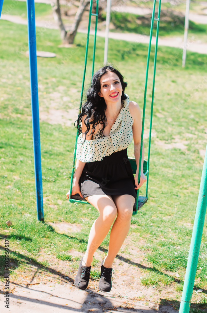 Beautiful Girl, brunette with red lips. Spring , shooting in the Park . Wearing a dress and high heel shoes, kataetsya at kachele Beautiful Girl, brunette with red lips. Spring , shooting in the Park . Wearing a dress and high heel shoes, kataetsya at kachele