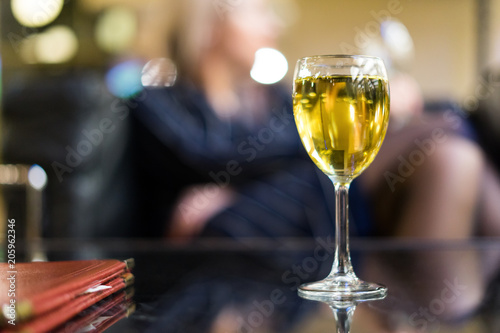 A glass of white wine against the background of a girl with a glass. The concept of going to a restaurant with a girl