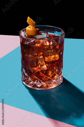 Negroni IBA cocktail, with gin, bitter, vermouth, in pop contemporary style, colorful, dark background.