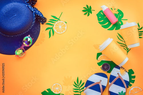 Summer vacation flat lay with tropical leaves, a refreshing drink, sunglasses, sunscreen, flip-flops, hat on a sunny yellow background with copy space