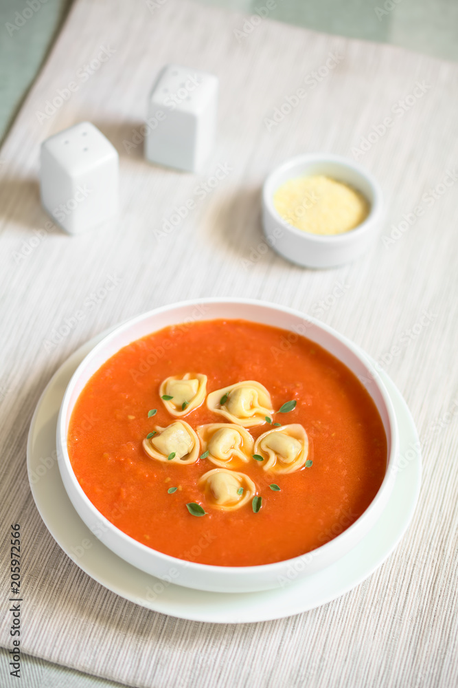 Hausgemachte frische Tomatencremesuppe mit Tortellini und frische Oreganoblätter, fotografiert mit natürlichem Licht (Selektiver Fokus, Fokus in die Mitte der Suppe) Hausgemachte frische Tomatencremesuppe mit Tortellini und frische Oreganoblätter, fotografiert mit natürlichem Licht (Selektiver Fokus, Fokus in die Mitte der Suppe)