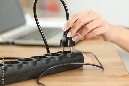 Woman hand plugging electric plug a in a socket