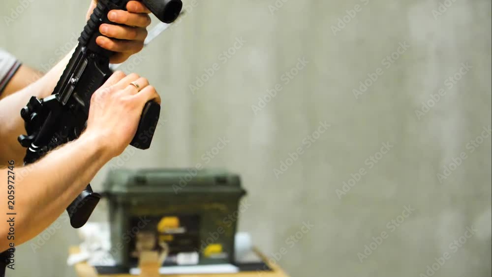 White male adult loads and cocks an assault rifle in slow motion at a shooting range White male adult loads and cocks an assault rifle in slow motion at a shooting range