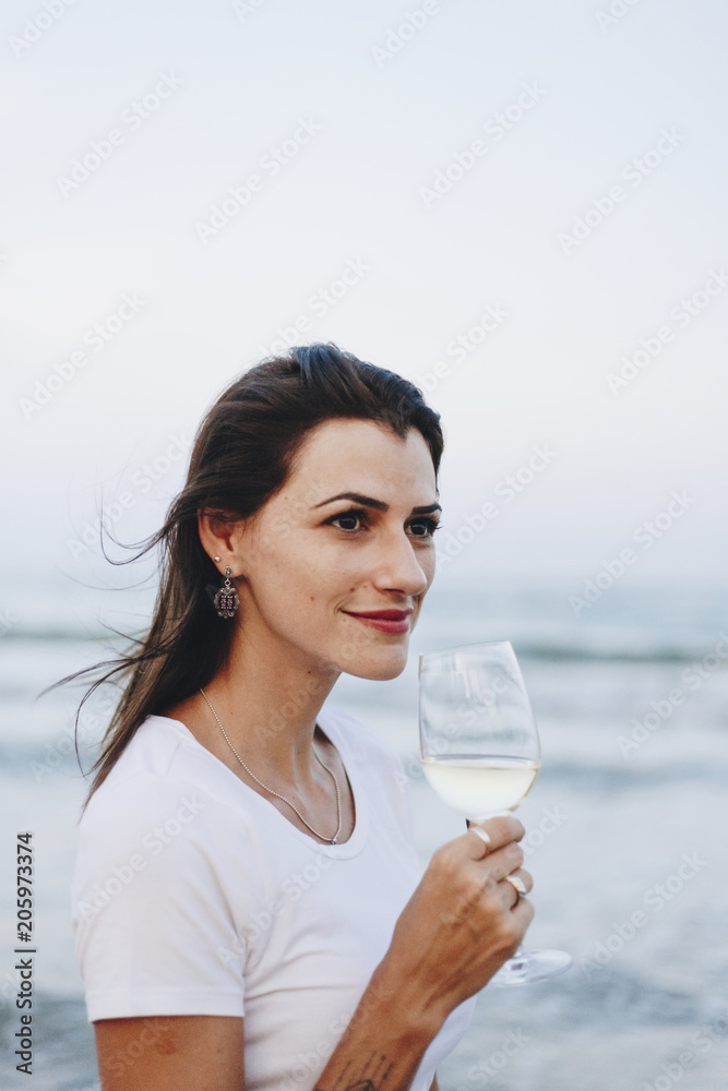 Woman drinking a glass of wine by the beach Woman drinking a glass of wine by the beach