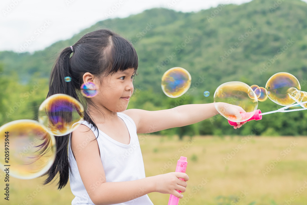 A little girl blowing soap bubbles in summer park. Background toninf for instagram filter. A little girl blowing soap bubbles in summer park. Background toninf for instagram filter.