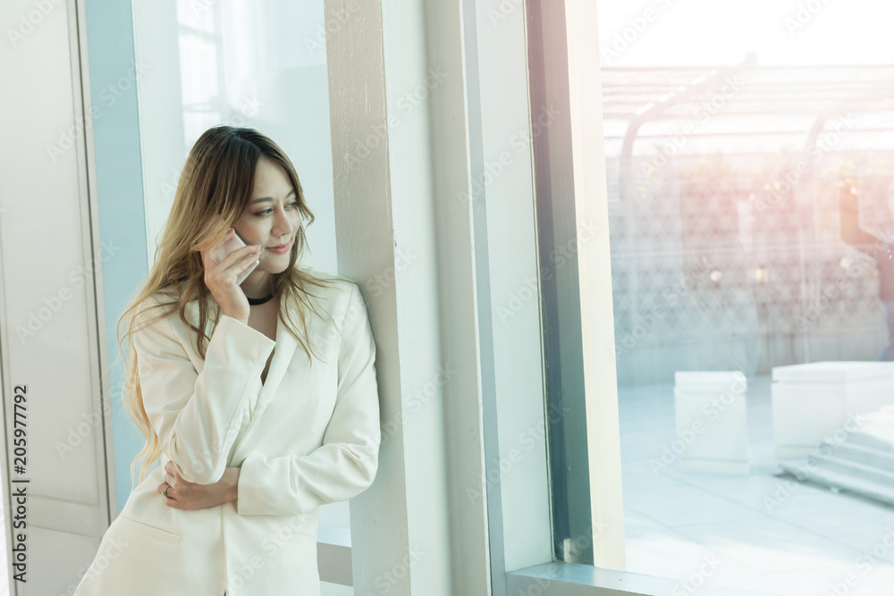 Beautiful women use the phone at the window. Beautiful women use the phone at the window.