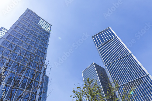 Bottom view of modern skyscrapers in business district against blue sky