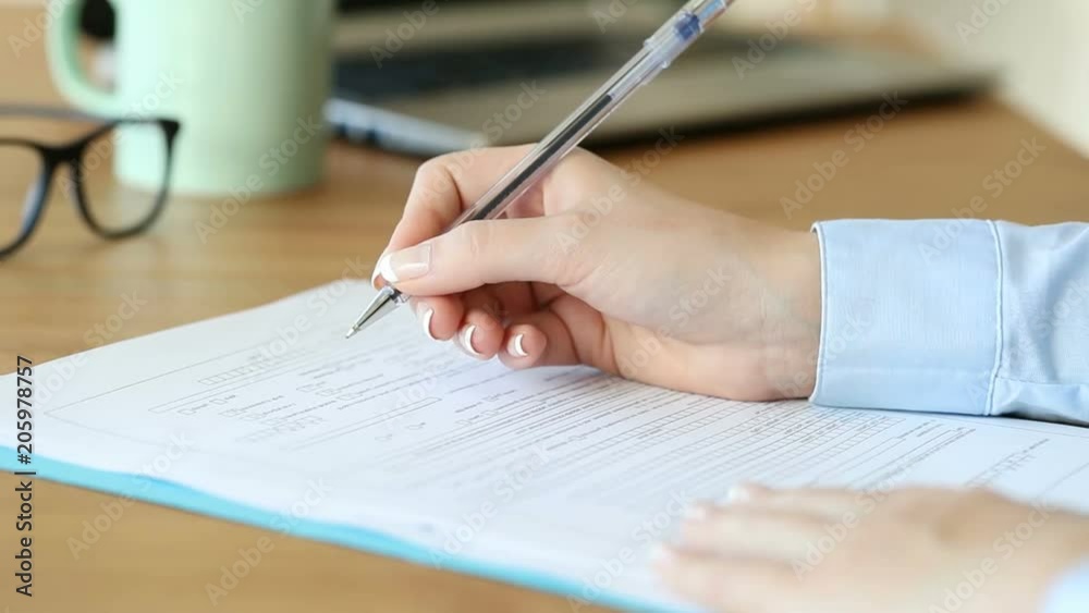 Close up of a woman hand filling form on a table at home or office