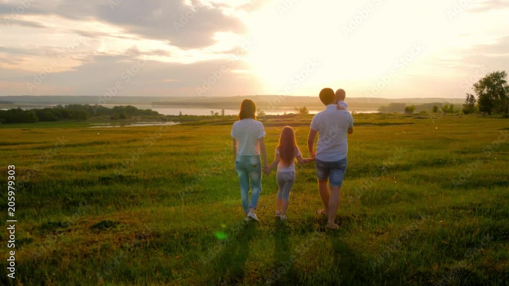 Happy Young Family with two children running on summer field. Healthy mother, father and little children enjoying nature together, outdoors at sunset. Happy Young Family with two children running on summer field. Healthy mother, father and little children enjoying nature together, outdoors at sunset.
