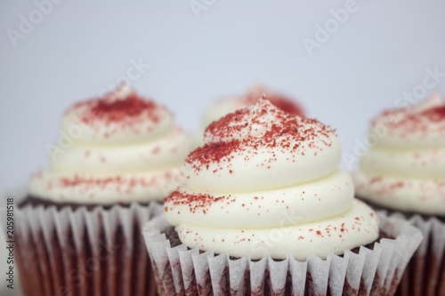Yummy red velvet cupcakes with white icing and sprinkles on an isolated white background
