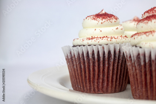 Yummy red velvet cupcakes with white icing and sprinkles on an isolated white background