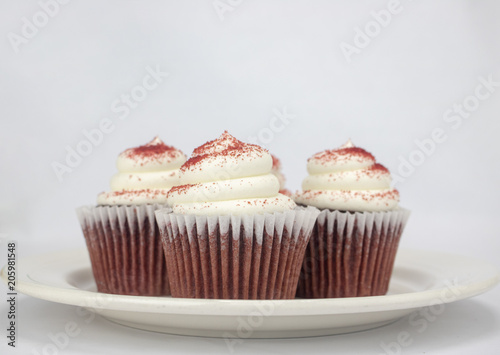 Yummy red velvet cupcakes with white icing and sprinkles on an isolated white background