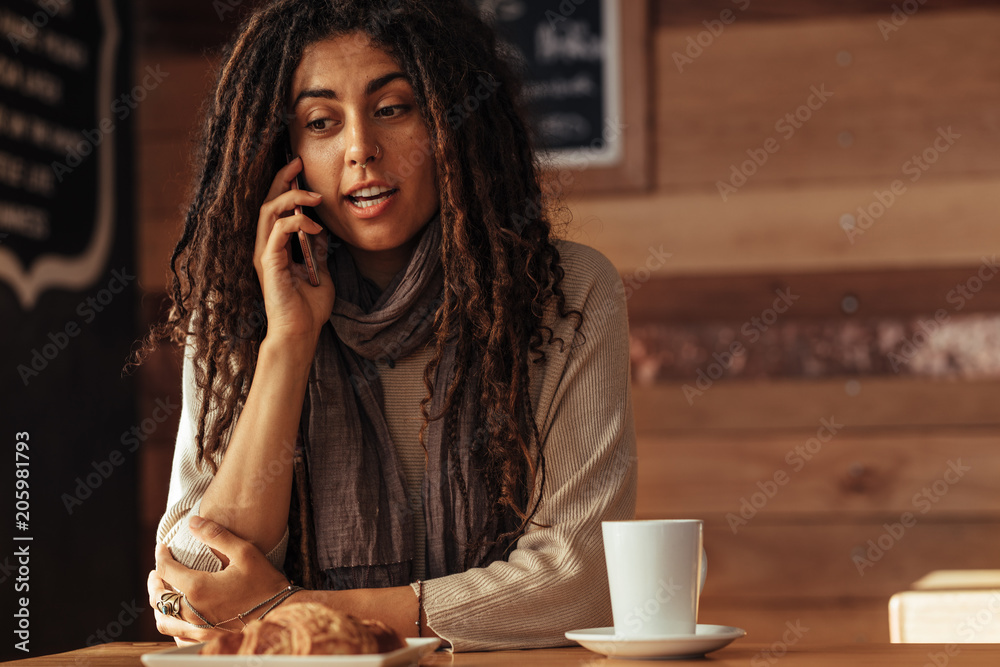 Woman talking over mobile phone at a cafe Woman talking over mobile phone at a cafe
