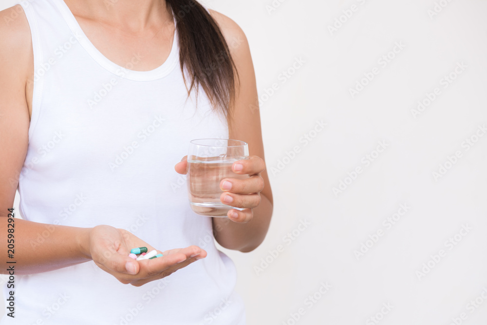 medicine, health care and people concept - close up of woman taking in pill and another hand holding a glass of clean mineral water. medicine, health care and people concept - close up of woman taking in pill and another hand holding a glass of clean mineral water.