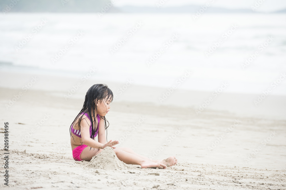 Happy child playing with sand at the beach in summer Happy child playing with sand at the beach in summer