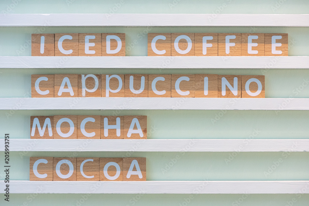 Iced coffee, cappuccino, mocha, cocoa, list of beverages, alphabet letter on wood block with pastel color wood wall.