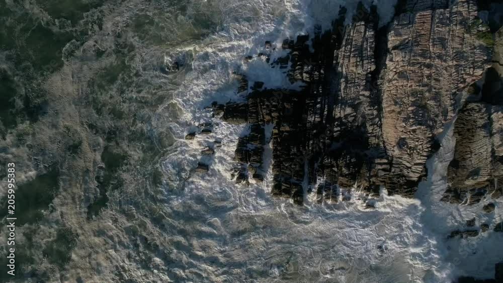 Slow motion aerial shot of waves crashing on a rocky shore Slow motion aerial shot of waves crashing on a rocky shore