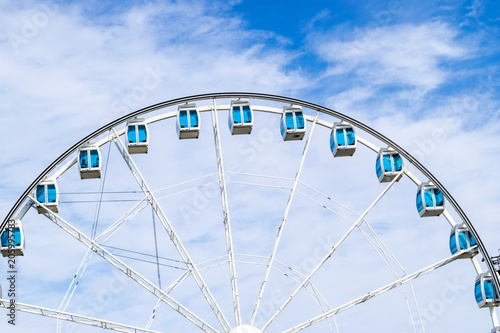Low angle view of a ferris wheel in an amusement park with a blue sky background. City park ferris wheel in Carousel Gardens. Holiday concept