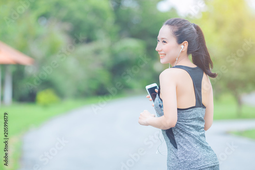 Obraz na płótnie portrait of a young asian woman doing outdoor exercise in park, She ran and listened to music from a mobile phone happily. w salonie
