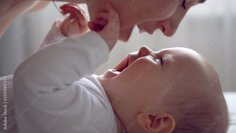 Mother kissing her adorable baby girl on bed