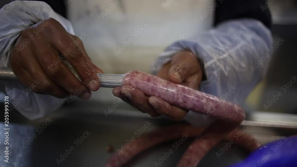 Close up of meat sausage being made in a butchery as casings are being filled by machine Close up of meat sausage being made in a butchery as casings are being filled by machine