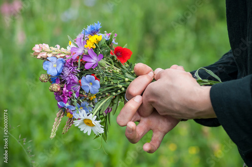 closeup of wild flowers bouquet in hand of young woman in a meadow