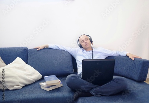man relaxes with headphones and laptop on the sofa