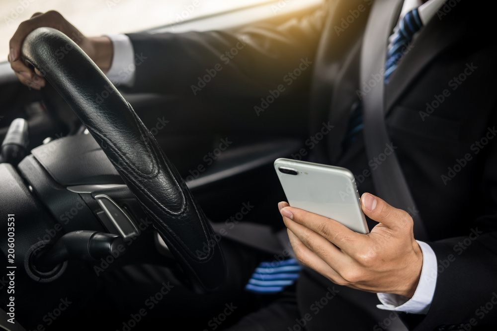 Attractive handsome young businessman using mobile smart phone in car Attractive handsome young businessman using mobile smart phone in car