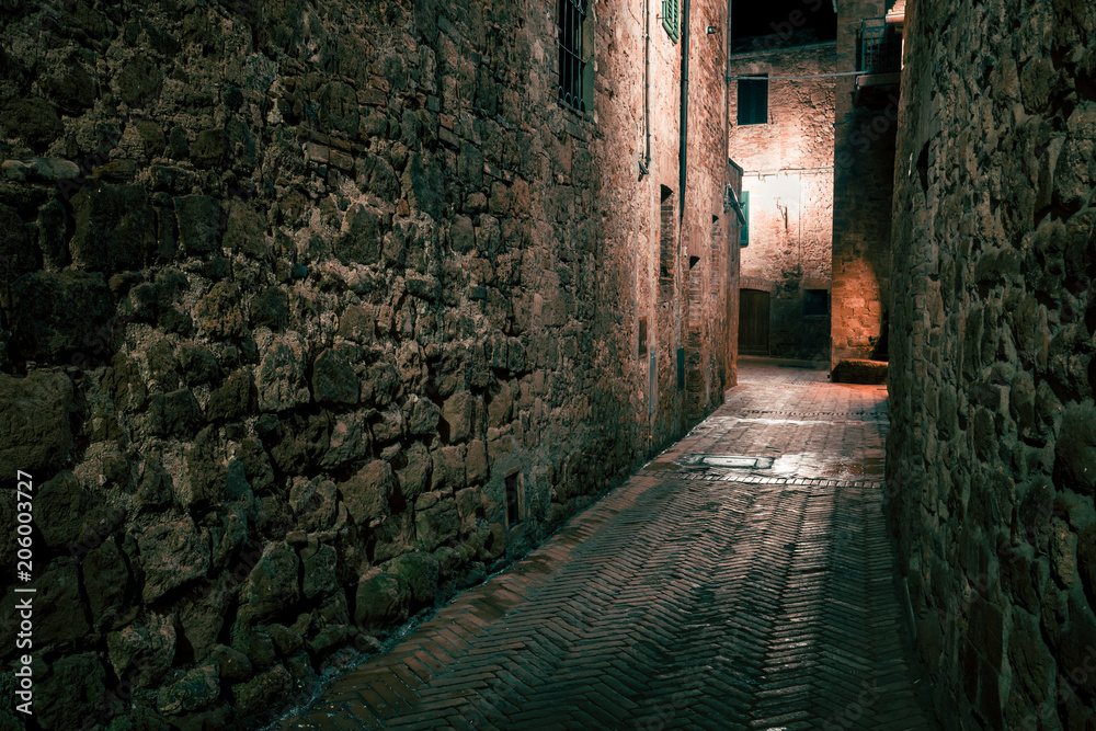 Old European narrow empty street of a medieval town at evening. Pienza, Italy