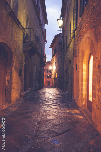 Old European narrow empty street of a medieval town at a foggy evening. Pienza  Italy
