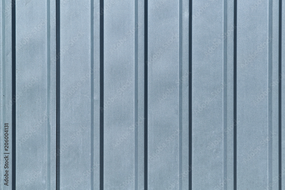 Sheet of ribbed galvanized metal for building structures. The surface has vertical protruding ribs for stiffness. It is used for covering roofs, for construction of fences. Background or backdrop. Sheet of ribbed galvanized metal for building structures. The surface has vertical protruding ribs for stiffness. It is used for covering roofs, for construction of fences. Background or backdrop.