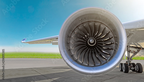 Aircraft jet engine close-up, airplane wing and chassis of landing gear wheel parked at the airport on a sky background, panorama. © aapsky