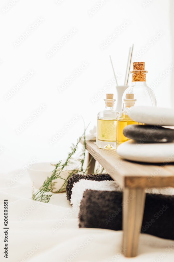 close up view of arrangement of spa treatment accessories with fern plant, towels, oil and salt on white background close up view of arrangement of spa treatment accessories with fern plant, towels, oil and salt on white background