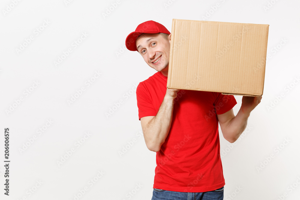 Delivery young man in red uniform isolated on white background. Male in cap, t-shirt, jeans working as courier or dealer holding empty cardboard box. Receiving package. Copy space for advertisement. Delivery young man in red uniform isolated on white background. Male in cap, t-shirt, jeans working as courier or dealer holding empty cardboard box. Receiving package. Copy space for advertisement.