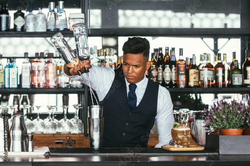 Expert bartender adding alcohol to a shaker photo