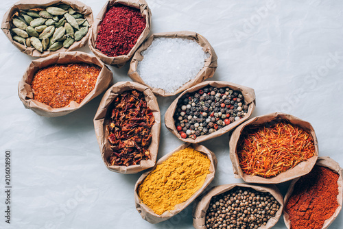 Fototapeta Naklejka Na Ścianę i Meble -  top view of colorful spices in paper bags on white table
