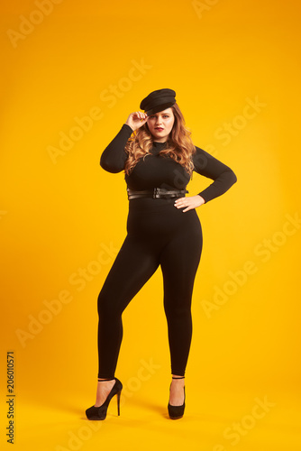 Tempting plus-size girl wearing stylish cap posing at camera